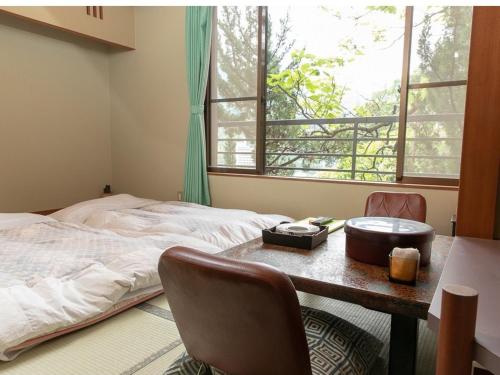 um quarto com uma mesa, uma cama e uma janela em Apolosou em Yugawara