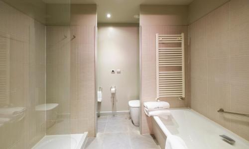 a bathroom with a tub and a toilet and a sink at Hotel Spa Attica21 Vilalba in Villalba