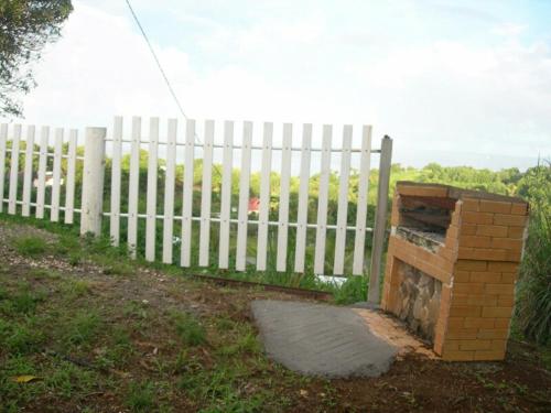 a brick oven next to a white fence at Gite Manmans in Goyave