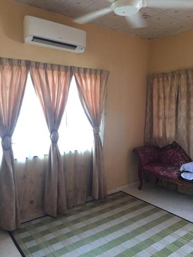 a room with a window with curtains and a couch at AMIMAS HOMESTAY in Kampong Telok
