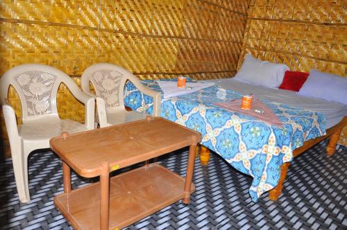 a room with two beds and two chairs and a table at Khushi Cottage in Hampi