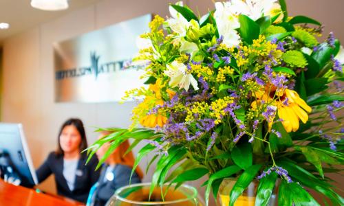 Un vaso di fiori su un tavolo con una donna di Hotel Spa Attica21 Villalba a Villalba