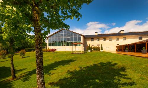 un grand bâtiment avec une pelouse devant lui dans l'établissement Hotel Spa Attica21 Villalba, à Villalba