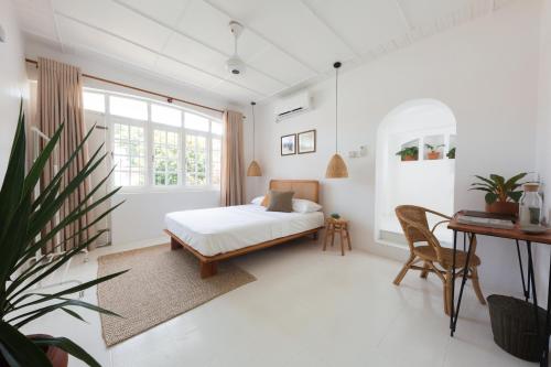 a white bedroom with a bed and a desk at Srilax in Colombo