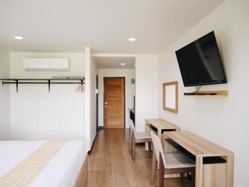 1 dormitorio con 1 cama, escritorio y TV en บ้านเพลิน en Nakhon Sawan