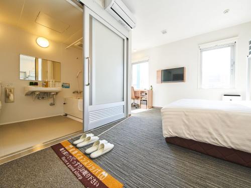 a hotel room with a bed and a bathroom at Super Hotel Mihara Ekimae in Mihara
