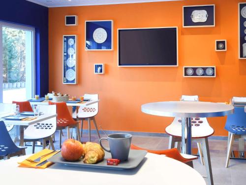 a dining room with tables and a flat screen tv at Ibis Styles La Louvière in La Louvière