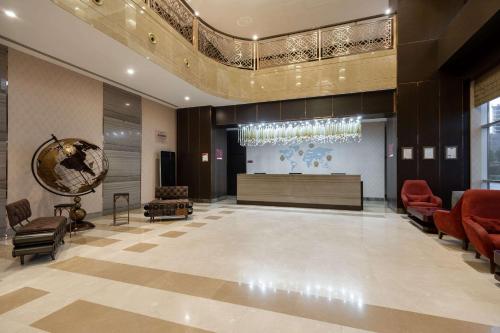 a lobby of a building with red chairs and a stage at Clarion Hotel Istanbul Mahmutbey in Istanbul