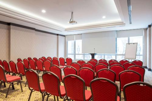 a conference room with red chairs and a podium at Clarion Hotel Istanbul Mahmutbey in Istanbul