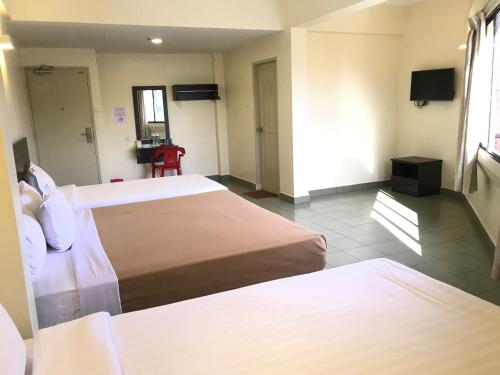 een hotelkamer met 2 bedden en een televisie bij Hotel Sitiawan in Sitiawan