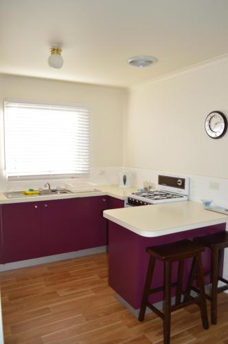 a kitchen with purple cabinets and a sink and a window at Waterfall Cottage in Rosebud