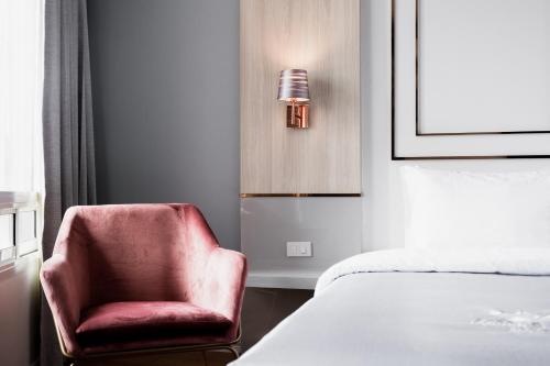 a bedroom with a red chair next to a bed at แจสเปอร์โฮเทล Jasper Hotel in Ban Phai