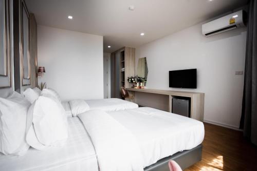 a hotel room with two beds and a television at แจสเปอร์โฮเทล Jasper Hotel in Ban Phai