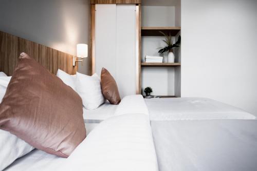 a bedroom with two white beds with brown pillows at แจสเปอร์โฮเทล Jasper Hotel in Ban Phai