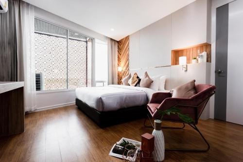 a hotel room with a bed and a chair at แจสเปอร์โฮเทล Jasper Hotel in Ban Phai