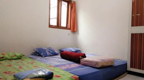 Una cama con almohadas en una habitación. en Jiddan Syariah RedPartner, en Lembang