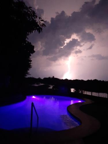 a lightning storm over a swimming pool with purple lights at Monty's Riverside View Resort in San Antonio