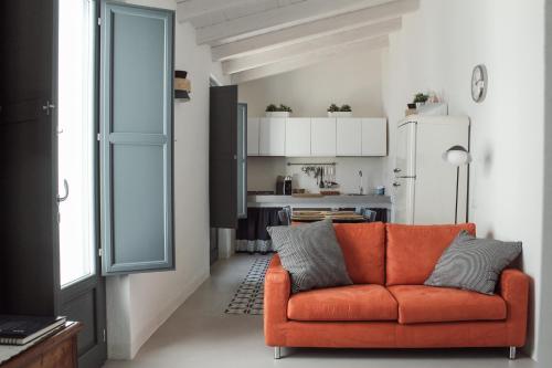 an orange couch in a living room with a kitchen at Casa Clementa in Pula