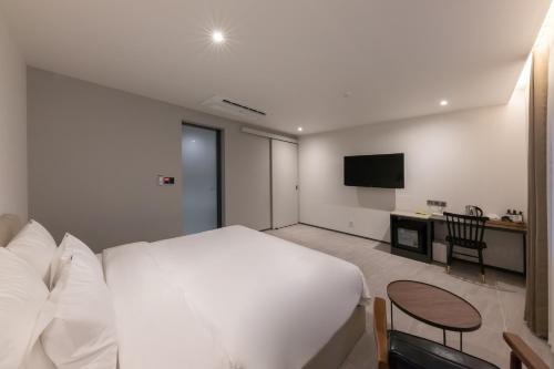 a bedroom with a large white bed and a television at Brown-Dot Hotel Dongchon Amusement Park in Daegu