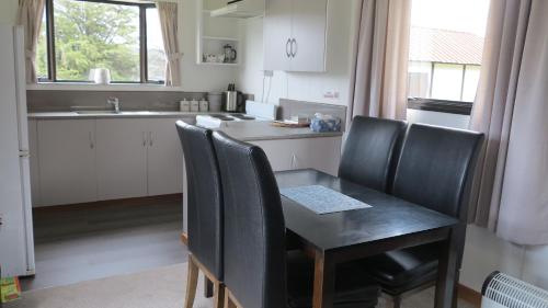 a kitchen with a black table and chairs and a counter at Tophouse Mountainview Cottages in Saint Arnaud