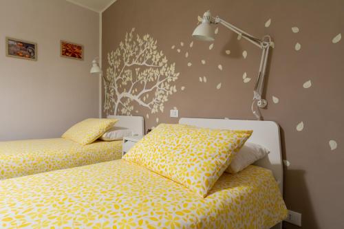 a bedroom with two beds with yellow sheets and a lamp at Le quattro stagioni in Levico Terme
