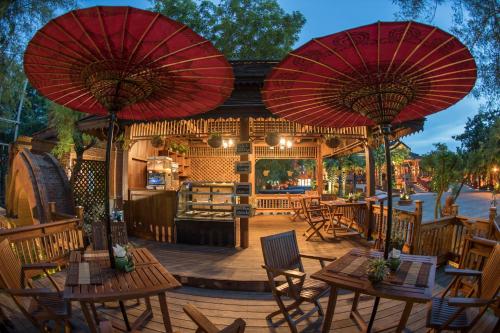 patio ze stołami, krzesłami i czerwonymi parasolami w obiekcie Heritage Bagan Hotel w mieście Pagan