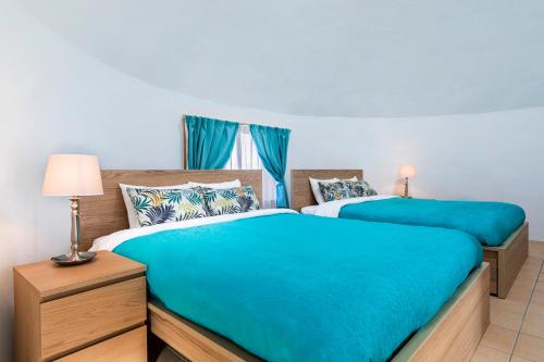 two beds in a bedroom with blue sheets at Uruma Dome Okinawa in Uruma