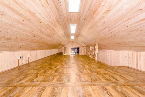 a large room with a wooden floor in a barn at Dongbackdongsan Pension in Jeju
