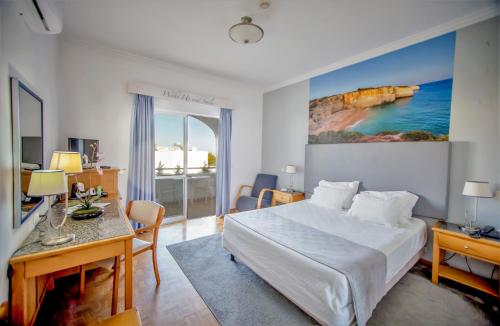 a hotel room with a bed and a desk and a table at Hotel Maritur - Adults Only in Albufeira