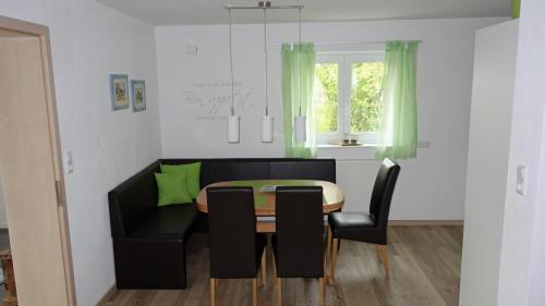 a dining room with a table and a black couch at Ferienwohnung Allgäuleben 68m2 in Amberg