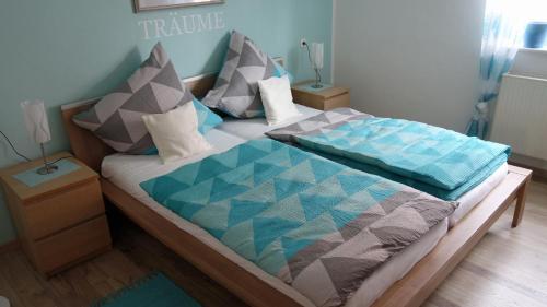 a bed with a blue and grey quilt on it at Ferienwohnung Allgäuleben 68m2 in Amberg