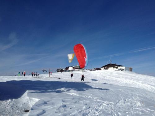 a group of people flying kites on a snow covered slope at Ferienwohnungen Vidoni in Bodensdorf