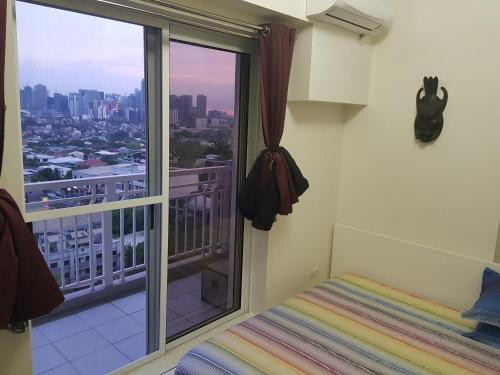 a bedroom with a balcony with a view of the city at Cucun's place in Manila