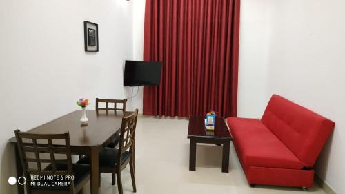 a living room with a red chair and a table at Azaiba Hotel Apartments in Muscat