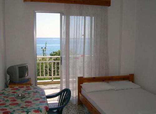 a bedroom with a bed and a window with a view at Apartments Ziogas in Paralía Skotínis