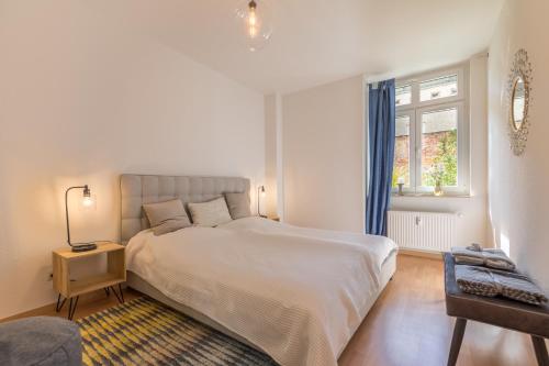 een slaapkamer met een groot wit bed en een raam bij Perle der Südvorstadt in Leipzig