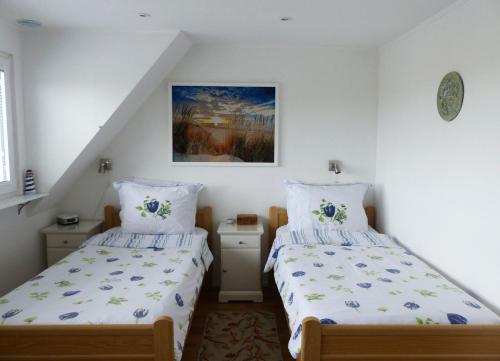 een slaapkamer met 2 bedden en een schilderij aan de muur bij B&B 'Four Seasons' in Julianadorp
