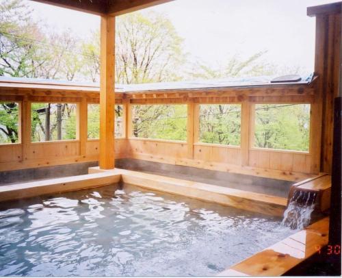een groot zwembad met water in een houten huis bij Hotel Ikaho Ginsui in Shibukawa