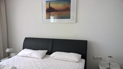 een bed met twee kussens en een schilderij aan de muur bij Ferienwohnung am Brasselsberg in Kassel