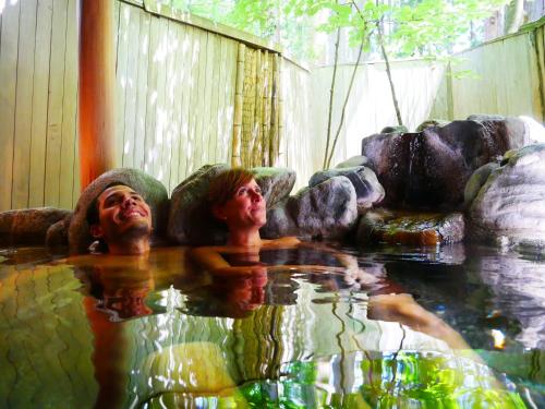 two people swimming in a pool of water at Ichirino Kogen Hotel Roan in Hakusan