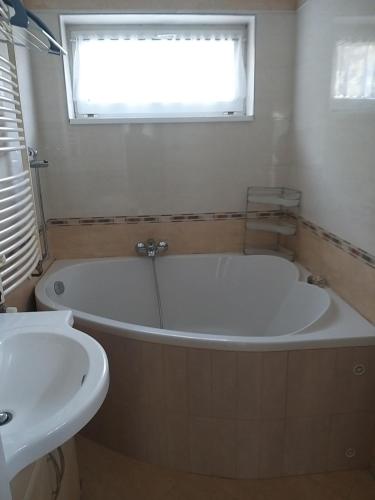 a bath tub and a sink in a bathroom at Franz Berg Apartman in Tököl
