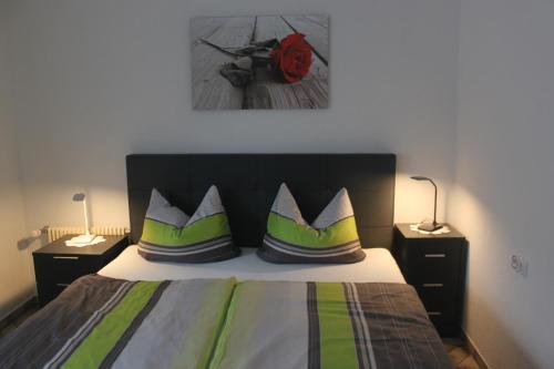 een slaapkamer met een bed met groene en witte kussens bij Ferienwohnung Angelika in Degerfelden