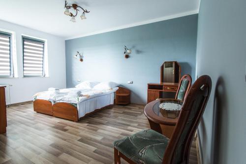 a bedroom with a bed and a table and a chair at Noclegi Na Granicy in Chyżne