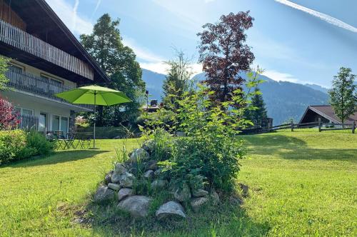 a garden with a green umbrella in a yard at Berghaus Anna Lisa in Mittelberg