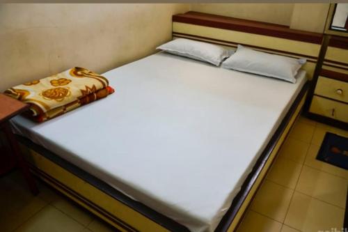 a large bed with white sheets and a pillow on it at Continental Guest House in Kolkata