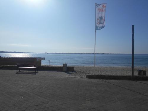 a bench sitting on the beach near the water at Les pieds dans l eau in Larmor-Plage
