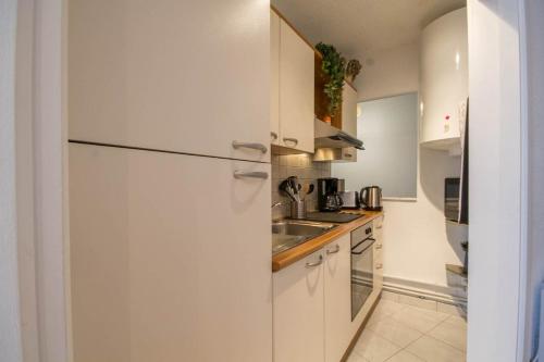 a white kitchen with a sink and a refrigerator at Les pieds dans l eau in Larmor-Plage