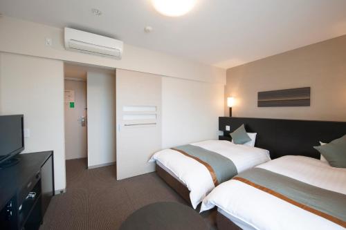 a hotel room with two beds and a television at Dormy Inn Premium Shimonoseki in Shimonoseki