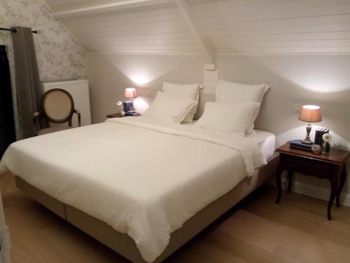 a bedroom with a large white bed with two tables at Cuerne bed&breakfast in Kuurne