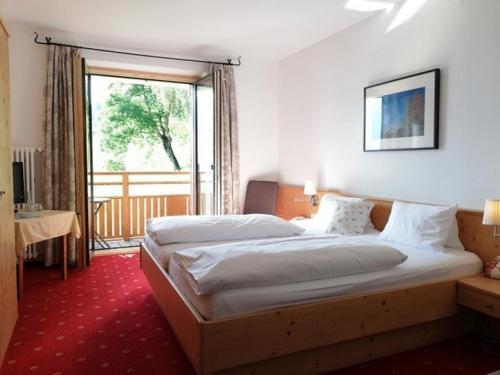 a hotel room with two beds and a large window at Hotel Bergerhof in Bartholomäberg
